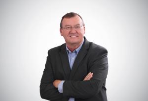 Wes Shattler, former FIS Vice President and Senior Partner, PCI Services at Payments Therapist, wearing a dark suit and blue shirt with his arms crossed.