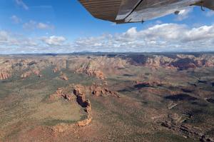 View from the airplane looking downward at beautiful red rocks and a vast desert landscape
