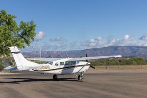 A Cessna 207 airplane sitting on a tarmac in front of the Mingus mountain range