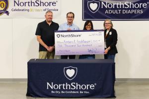 NorthShore founder and CEO Adam J. Greenberg and partners hold an oversized $6,200 check for Northern Illinois Food Bank in front of NorthShore Adult Diapers banners.