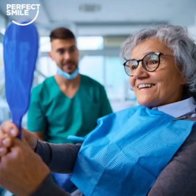 Older woman holding a dental mirror during a dental appointment with a dentist in the background.
