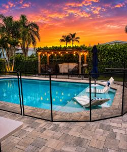 Beautiful Florida pool home featuring a tropical backyard, private swimming pool, wooden pergola, palm trees, and stunning sunset views, showcased by Joe Tumolo, Treasure Coast Realtor.