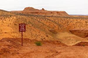 A singular sign post in the middle of untouched desert landscape stating "off limits, no one beyond this point"