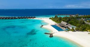 Aerial view of Grand Park Kodhipparu Maldives, showing turquoise lagoon waters, white-sand beaches, overwater villas and the resort's infinity pool overlooking the Indian Ocean.