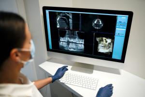 Dental professional using advanced digital imaging technology to examine a patient's jaw scan on a computer