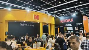 Visitors at a Kodak booth with yellow and black signage and home display products.