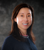 An Asian woman with brown hair smiling at the camera.