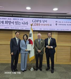 Four forum participants stand beside a Korean flag beneath a "Beyond GDP to GDH" banner at Korea's National Assembly.
