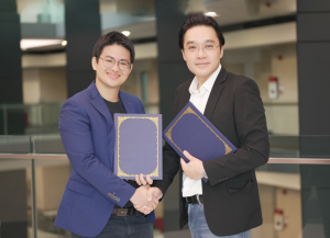 Kevin Chan and Richard Liew smile as they shake hands and hold certificates