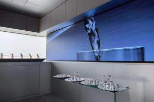 Inside the Nomad Luxe Walk-In L: a long LED screen, a lit shelf of UPDATE cans and a glass tasting table with silver cups