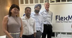 FlexM leadership team standing in front of the FlexM logo at the company's office
