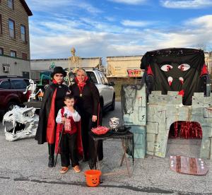 Two adults and a kid dressed as vampires with a small haunted house in the West Ridge Center parking lot.