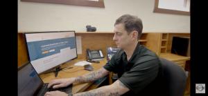 Quick Strike Media team member working at a desk in the Palestine, Texas office, typing on a laptop beside a monitor that displays a local service business website under development.