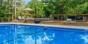 Outdoor pool at Forest Springs Resort in Eureka Springs, with wooden decks, lounge seating, a fire bowl and string lights among tall trees.