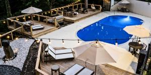 Aerial view of the outdoor pool at Forest Springs Resort at dusk, with wooden decks, lounge seating, umbrellas and string lights.