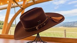 The Aspen in Chocolate from the exclusive HeadWest Reserve Collection, a Western Cattleman hat featuring a braided band, decorative metal accents, and tassel, designed in collaboration with Tacchino Hat Co.