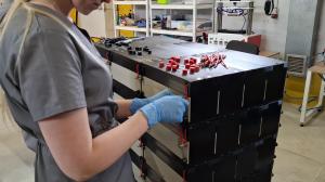 A technician wearing blue gloves assembles stacked SorbiForce battery modules.
