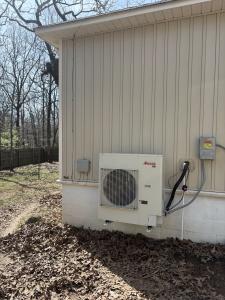 Wall-mounted Amana R32 outdoor HVAC unit on a brick home exterior next to an electric meter and electrical box in Cabot, Arkansas.