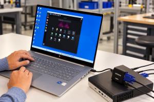 Technician using a laptop and Cytrence Kiwi+ VGA adapter to control a mini PC through a direct VGA connection, providing a portable alternative to a traditional IT crash cart.