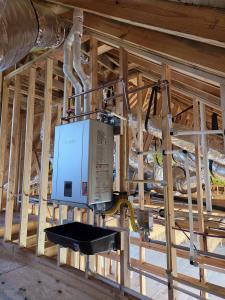 Tankless water heater with copper water lines, gas line, venting, and drain pan installed in a new Brazoria County, Texas home under construction