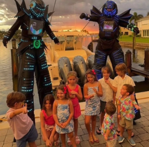 Children by water with stilt walkers