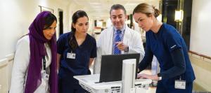 KFSH physicians and nurses gathered around a computer workstation in a hospital corridor