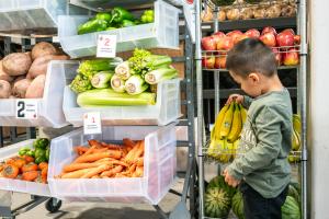 Young boy selecting bananas from a rack of fresh fruit and vegetables at a community food pantry