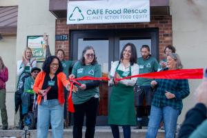 Group of smiling people cutting a red ribbon outside the CAFE Food Rescue building entrance