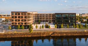 Multi-storey timber hybrid office building on a riverbank at sunset