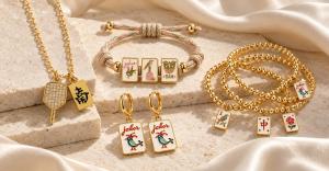 Born to Rally Mahjong jewelry featuring gold tile charm necklaces, colorful cord bracelets, gold beaded bracelets and Joker tile earrings on ivory stone.