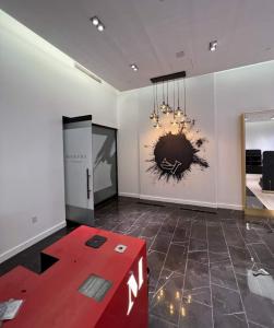 Modern commercial interior with freshly painted white walls, dark tile flooring, a red front counter, pendant globe lighting, and decorative wall artwork.