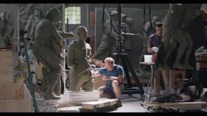 Sabin Howard crouches beside a clay soldier while Charlie Mostow works on another figure in the crowded sculpture studio.