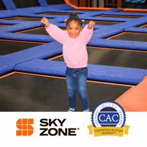 Smiling girl in pink sweatshirt raises her arms at Sky Zone trampoline park, with Certified Autism Center badge visible.