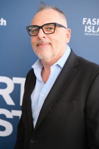HEROIC film composer Imre Czomba wearing black glasses, a dark jacket and a light blue shirt on the blue carpet at the 2026 Newport Beach Film Festival.