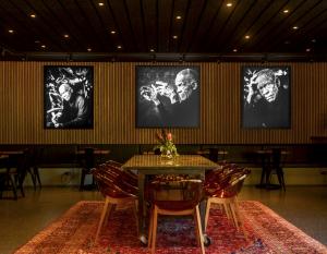 three black and white portraits hang on the wall of a dining space with tables and cafe chairs.