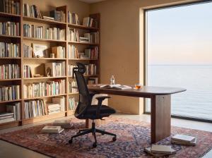 Black OTTUNI Arix ergonomic chair at a wooden desk in a bedroom home office.