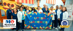 Group of healthcare workers holding an “Autism Awareness” banner, with Memorial Healthcare System and CAC logos.