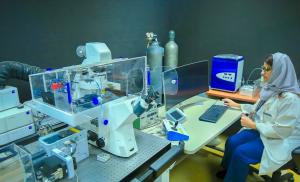 A KFSH researcher at a computer beside advanced microscopy equipment in a laboratory in Riyadh