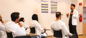 A KFSH instructor leading a training session for clinicians in white coats in Riyadh