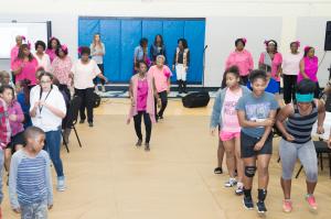 Myra Jones, senior adult line dancers, and Love Ministries youth dance together in the foreground while Karla Nivens sings in the distance.