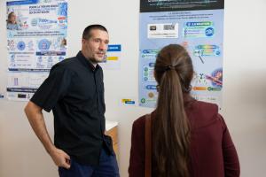 Rémi Vernet discussing CNS-targeted encapsulated cell technology with an attendee in front of the award-winning research poster at Geneva University Hospitals Innovation Day.