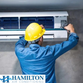 Technician installing a wall-mounted air conditioning unit