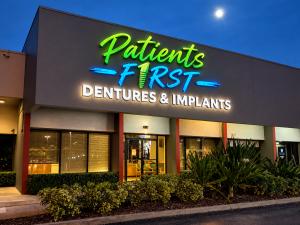 Exterior of Patients First Dentures and Implants in Miami Lakes at night with illuminated sign
