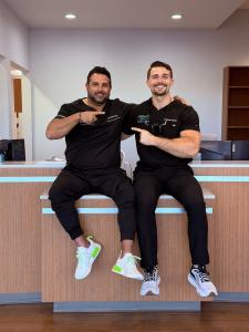 Dr. Daniel Fenton and Dr. Cole Herzik sitting on the front desk at Patients First Dentures and Implants