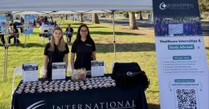 Two IMA representatives behind the International Medical Aid table and banner at the UC Davis Pre-Health Fair