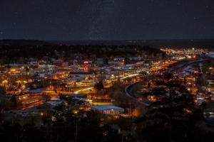 A star-filled night sky stretches above the warm glow of downtown Flagstaff, Arizona.