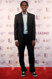 A.C. Green poses on the red carpet in front of the Hollywood Park Casino backdrop.