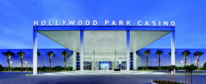 File photo of Hollywood Park Casino's illuminated entrance and palm trees at dusk.