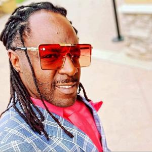 Author Kurt Glasgow wearing red sunglasses and a blue pinstripe jacket.