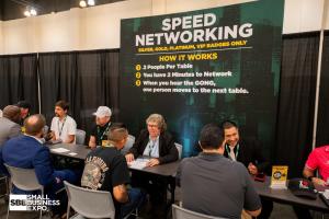 Attendees sit across from one another at tables beneath a Speed Networking sign at a previous Small Business Expo.